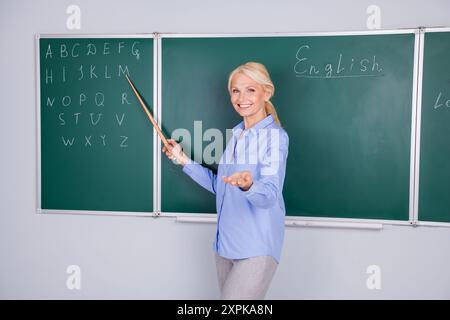 Foto einer charmanten intelligenten Seniorin trägt Hemdarbeit in der Schule erklärt Lektion isoliert auf grünem Bretthintergrund Stockfoto