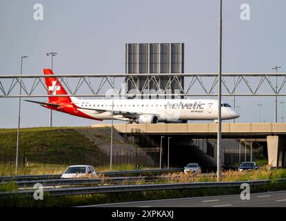 Flughafen Amsterdam Schiphol, Helvetic Airways Embraer ERJ-195, Flieger auf dem Rollweg, Brücke über die Autobahn A4, Verbindung von der Polderbaan Runway zum Terminal, Niederlande, Amsterdam Schiphol *** Amsterdam Schiphol Airport, Helvetic Airways Embraer ERJ 195, Flugzeug auf dem Rollweg, Brücke über die Autobahn A4, Verbindung von der Start- und Landebahn Polderbaan zum Terminal, Niederlande, Amsterdam Schiphol Stockfoto