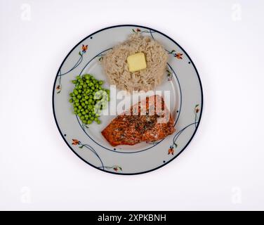 Gebackener pazifischer Lachs mit Pfeffer, Dill und Kaperngarnitur, Erbsen und Jasminreis mit Buttertupfer auf weißem Hintergrund Stockfoto