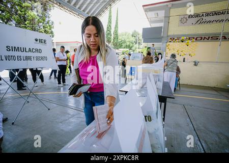 Eine Person legt ihre Stimmzettel in die Wahlbox eines Wahlhauses, das während der mexikanischen Präsidentschaftswahlen in einer Schule eingerichtet wurde. Das Bild spiegelt den Wechselstrom wider Stockfoto