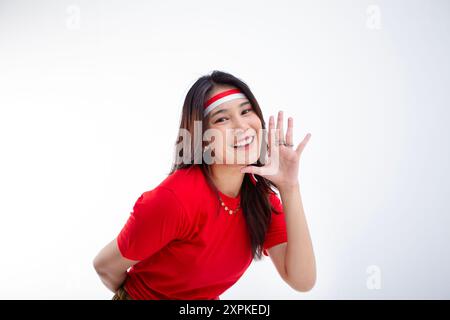 Schöne Frau mit langen Haaren rotes T-Shirt Konzept der indonesischen Unabhängigkeit die Frau trägt ein rot-weißes Stirnband und flüstert mir etwas Stockfoto