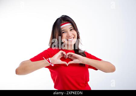 Hübsches Mädchen in Rot, das ihre Brust liebt und fröhlich lächelt, Frauenwerbung für das Konzept des indonesischen Unabhängigkeitstags Stockfoto