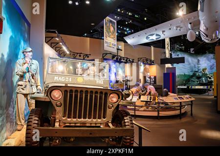 National Museum Of The Marine Corps World War II Exhibit Triangle Virginia | TRIANGLE, Virginia — Eine World-War-II-Galerie im National Museum of the Marine Corps stellt einen Kommandoposten des Pazifikkriegsgebietes nach, mit einem Kriegsjeep mit der Markierung "MAG-24 HQ" neben Schaufensterpuppen und einem zeitgenössischen "Enlist Now"-Rekrutierungsposter. Die Ausstellungen in diesem Flügel stützen sich auf Artefakte wie den leichten M3A1 Stuart-Panzer und die 37-mm-Panzerabwehrkanone, um die Marineskampagnen auf Guadalcanal, Tarawa, Saipan, Iwo Jima und Okinawa nachzuzeichnen. Stockfoto