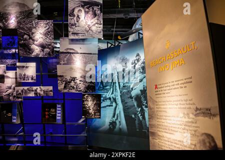 National Museum Of The Marine Corps Iwo Jima Exhibit Triangle Virginia | TRIANGLE, Virginia — Eine Wand mit Archivfotos neben dem Panel "Strandangriff, Iwo Jima“ im National Museum of the Marine Corps dokumentiert die Invasion von 1945, von Landungsbooten, die sich dem Ufer nähern, bis zu den Nachwirkungen im vulkanischen Gelände der Insel. Die Ausstellung erzählt, wie die Marinedivisionen unter Corsair-Luftunterstützung und navaler Artillerie Feuer gegen die Verteidigungsanlagen landeten, die von General Tadamichi Kuribayashi befehligt wurden. Stockfoto
