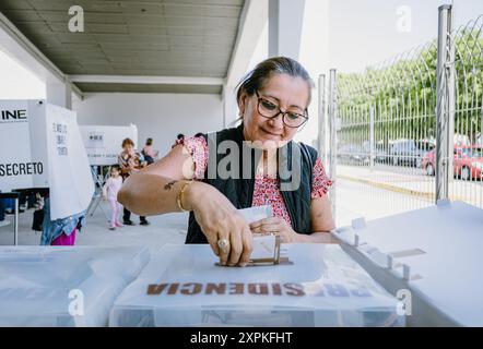 Eine Person legt ihre Stimmzettel in die Wahlbox eines Wahlhauses, das während der mexikanischen Präsidentschaftswahlen in einer Schule eingerichtet wurde. Das Bild spiegelt den Wechselstrom wider Stockfoto