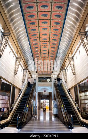 WASHINGTON, DC, USA – das Hauptatrium und die Rolltreppen im unteren Stockwerk des Smithsonian National Postal Museum in Washington, DC. Diese Ansicht zeigt das mehrstöckige Design des Museums, wobei die Rolltreppen einen einfachen Zugang zwischen den Stockwerken ermöglichen. Das offene Atrium ermöglicht es Besuchern, die Pracht des Raumes zu genießen und hängende Exponate aus verschiedenen Perspektiven zu betrachten. Stockfoto