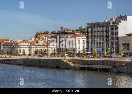 Blick von der Santa Clara Brücke mit dem Wasser des Mondego River im Vordergrund des Bahnhofsgebäudes (Estação Comboios), Coimbra. Stockfoto