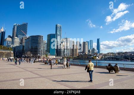 Sydney Circular Quay und Sydney Harbour mit Touristen, die neben dem Hafen und Bürohochhäusern laufen, Sydney, NSW, Australien Stockfoto