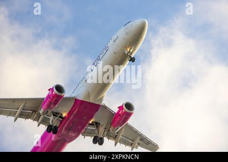 Unter dem Bild eines wizz Air airbus a321 231, der in einen bewölkten Himmel aufsteigt Stockfoto