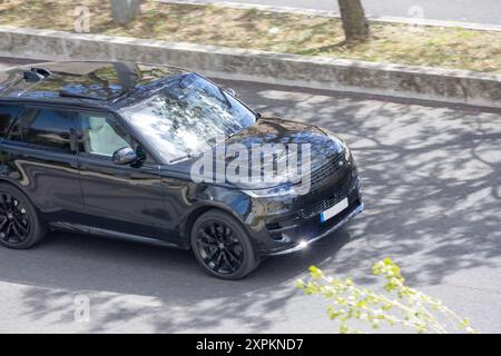 Schwarzer Range rover fährt an einem sonnigen Tag mit Bäumen in den Fenstern Stockfoto