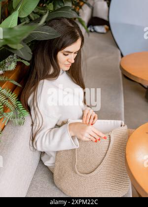 Attraktive Frau, die mit einem Strohbeutel in einem Café sitzt Stockfoto