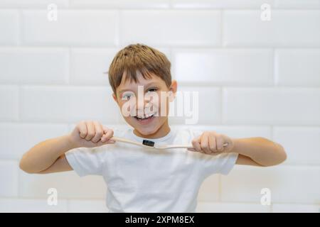 Süßer 8-jähriger Junge, der Bambuszahnbürsten hält und in die Kamera schaut Stockfoto