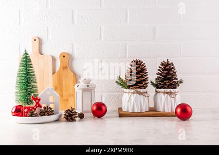 Home Countertop Küche Weihnachtsdekorationen, Kugeln, ein Mini-Weihnachtsbaum, eine Laterne, ein Kegel in einer Schüssel, große Zedernkegel in einem Topf. Vorderansicht. Stockfoto