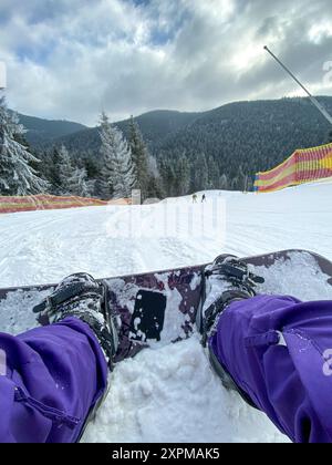 Frau, die mit Snowboard auf Schnee liegt Stockfoto