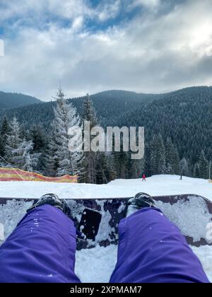 Frau, die mit Snowboard auf Schnee liegt Stockfoto