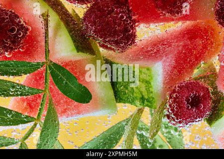 Frische Wassermelone und Himbeeren mit grünen Blättern, getaucht in sprudelnde Blasen. Erfrischendes Sommererlebnis. Stockfoto