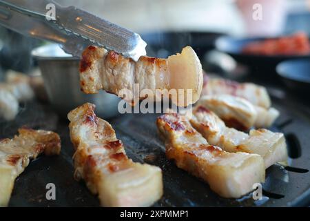 Gegrillter Schweinebauch wird auf schwarzem Grill gegrillt, Nahaufnahme Stockfoto