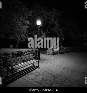 Cres, Kroatien - 8. April 2023: Weg am Meer in der Nacht, Straßenlaterne, schwarz-weiß, Parkbank Stockfoto