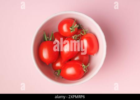 Rote Kirschtomaten in Schüssel auf rosa Hintergrund. Draufsicht. Stockfoto