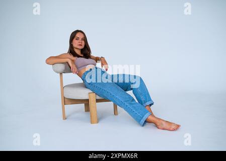 Das Mädchen sitzt auf einem Stuhl und lehnt sich auf den Rücken Stockfoto