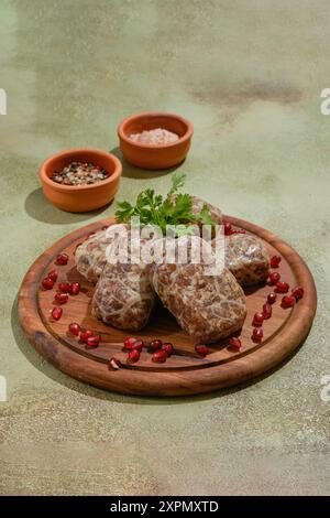 Traditionelle georgianische Roh-Rinderkoteletts: Apkhazura mit Gewürzen und Kräutern, verziert mit Granatapfelkernen und Koriander Stockfoto