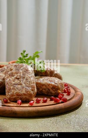 Nahaufnahme der traditionellen georgianischen Roh-Rindfleischkoteletts - Apkhazura, umwickelt in ein mit Granatapfelkernen verziertes Fettnetz Stockfoto