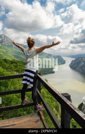 Das Mädchen steht mit ausgestreckten Armen am Aussichtspunkt Ploce an der Donau in der Djerdap-Schlucht Stockfoto