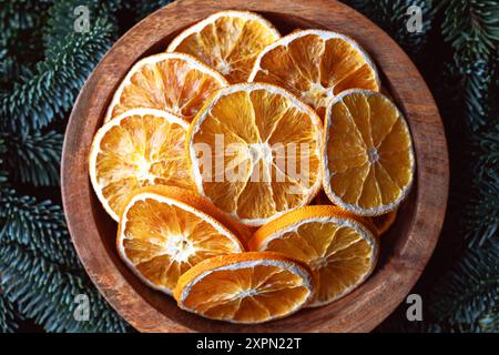 Draufsicht auf getrocknete Orangenscheiben in Holzkiste mit Tannenzweigen und Tannenzapfen aus nächster Nähe. Weihnachten oder Neujahr Hintergrund Stockfoto