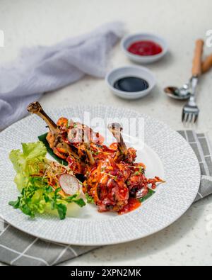 Ein Teller mit saftigen, glasierten Hähnchenflügeln mit knuspriger Haut, auf einem Bett mit frischem Salat und Radieschen-Sprossen Stockfoto