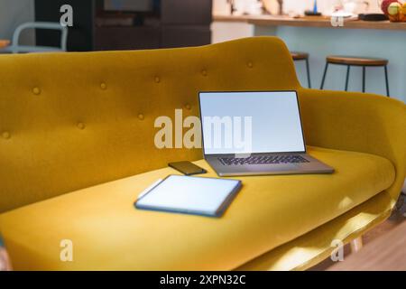 Gemütliches Sofa mit Laptop und Grafiktablett. Leeres Modell des weißen Bildschirms reinigen. Wohnraum. Stockfoto