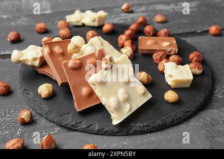 Verschiedene leckere Schokolade mit Nüssen auf dunklem Holzhintergrund Stockfoto