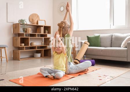 Junge sportliche Frau mit ihrer kleinen Tochter, die zu Hause Yoga praktiziert Stockfoto