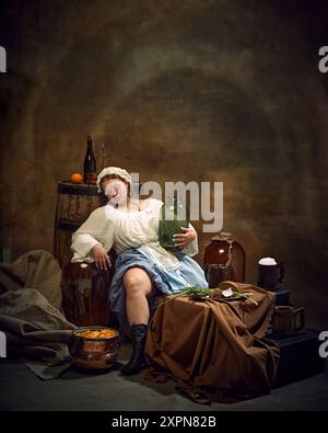 Frau in traditioneller Kleidung entspannt sich mit Kanne in der Hand, umgeben von rustikalen Artikeln wie Fässern und einfachen Speisen in ruhiger, heimeliger Atmosphäre. Stockfoto