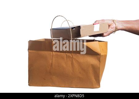 Die Hand der indischen Frau, die Pizzakarton aus brauner Papiertüte auf weißem Hintergrund herausnimmt. Lieferkonzept Stockfoto