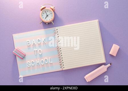 Rosafarbener Wecker und Notizbuch mit Schulworten Stockfoto
