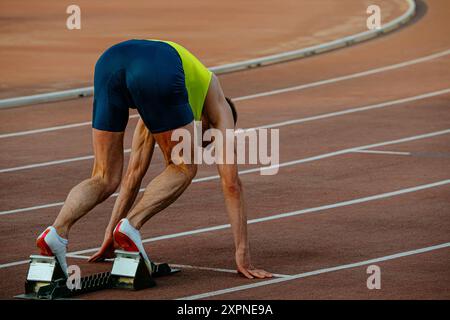 Männlicher Läufer in Startblöcken Sprint-Rennen Stockfoto