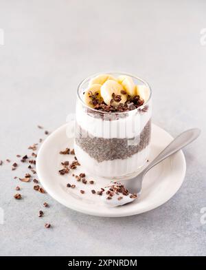 Chia-Pudding auf Pflanzenbasis mit rohen Kokosjoghurt und Kakaonibs und Banane, Kopierraum Stockfoto