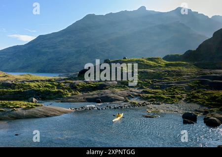 Ein Kajakfahrer auf Loch Coruisk in der Nähe der Trittsteine über dem Scavaig River. In den Cuillin Mountains, Isle of Skye, Schottland, Großbritannien. Stockfoto