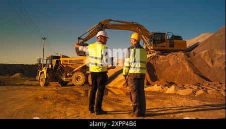 Rückansicht Eines Kaukasischen Immobilieninvestors Mit Tablet Und Projektmanager, Der Auf Einer Industriebau Spricht. Kollegen, Die Schutzhüte Tragen Und Heavy Machinery Bei Der Arbeit Zusehen. Sonniger Tag Stockfoto