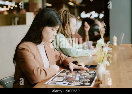 Junge Frau liest Menü im gemütlichen Restaurant Stockfoto
