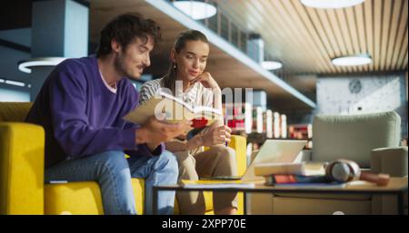 Porträt von zwei glücklichen Schülern, die in einem Campus-Besprechungsraum ein Gespräch führen und an einem Schulprojekt zusammenarbeiten. Männlich und weiblich mit Laptop-Computer, recherchieren Lehrbücher und Planungsarbeit Stockfoto