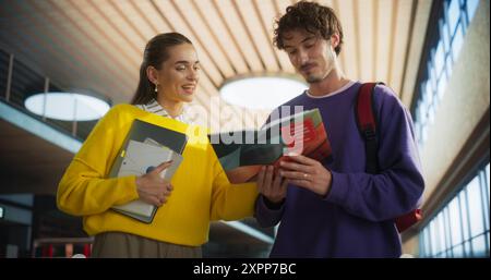 Universitätsbibliothek: Clevere, fröhliche Klassenkameraden, die sich unterhalten, lernen, gemeinsam für Prüfungen studieren. Junge Männer und glückliche Frauen bereiten sich auf eine Klassenaufgabe vor und unterhalten sich vor der Vorlesung auf dem Campus Stockfoto