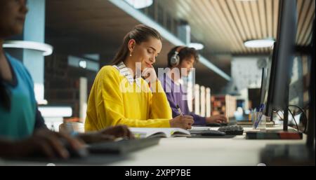 Gruppe von verschiedenen Gymnasiasten, die einzeln in einer öffentlichen Bibliothek studieren. Junge Menschen, die hinter Computern arbeiten, Lehrbücher lesen, Notizen in Notizbüchern machen, Essays schreiben und Vorlesungen vorbereiten Stockfoto