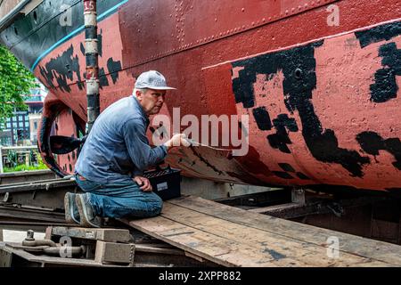 Crraftsman Painting Ship Craftsman Painting the Hull of a Historical Steam Thug auf der historischen Werft von Koningspoort. Rotterdam, Niederlande. Rotterdam Oude Haven / Koningspoort Zuid-Holland Nederland Copyright: XGuidoxKoppesxPhotox Stockfoto