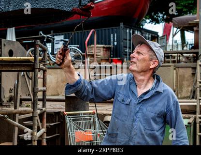 Crraftsman Painting Ship Craftsman Painting the Hull of a Historical Steam Thug auf der historischen Werft von Koningspoort. Rotterdam, Niederlande. Rotterdam Oude Haven / Koningspoort Zuid-Holland Nederland Copyright: XGuidoxKoppesxPhotox Stockfoto