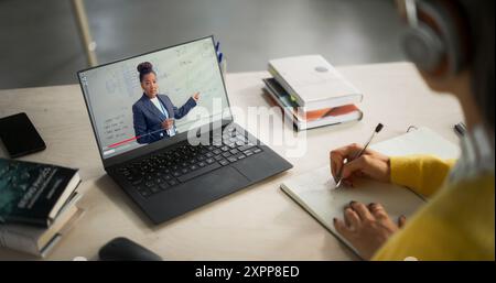 Over-the-Shoulder-Aufnahme mit einem Studenten, der in einer Bibliothek Ingenieurwissenschaften studiert. Anonymes Lernen für Frauen Online, Vorbereitung auf technische Prüfungen Stockfoto