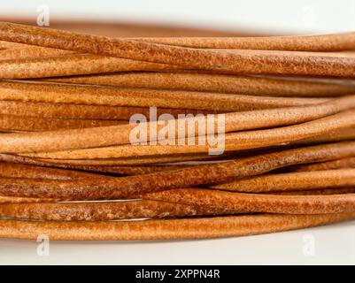 Nahaufnahme einer Spule aus natürlichem gegerbtem Leder, die in feine Streifen geschnitten ist, für Schnürbänder und Bastelarbeiten Stockfoto