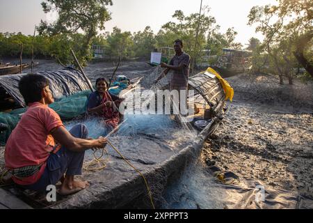 Leute reparieren Fischernetze auf einem Boot, Pakhiralay, in der Nähe von Gosaba, South 24 Parganas District, West Bengalen, Indien, Asien Stockfoto