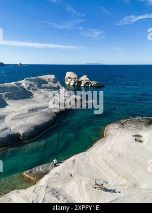 Aus der Vogelperspektive des Menschen mit dem Fahrrad am Strand von Sarakiniko mit seinem grau-weißen Vulkangestein mit Bucht und Küste, Sarakiniko, Milos, Südägäis, Griechenland, Stockfoto