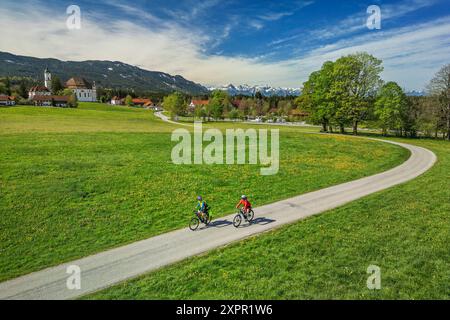 Mann und Frau Radfahren auf dem Bodensee-Königssee-Radweg mit Wieskirche im Hintergrund, wies, UNESCO-Weltkulturerbe Wieskirche, Oberbava Stockfoto